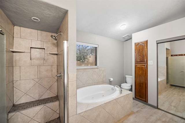 bathroom featuring toilet, a tub with jets, a stall shower, and a textured ceiling