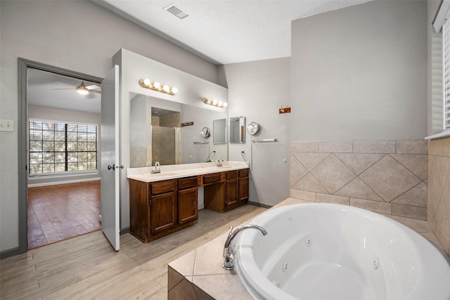 full bathroom featuring a sink, visible vents, a tub with jets, and wood finished floors