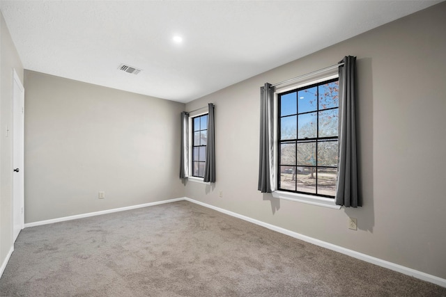 spare room featuring carpet flooring, visible vents, and baseboards