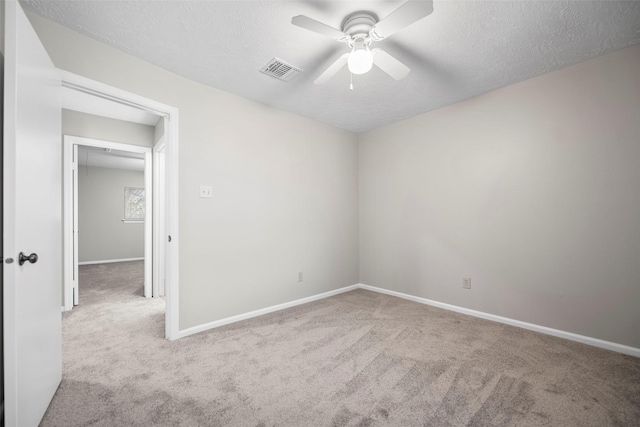 empty room with baseboards, visible vents, ceiling fan, a textured ceiling, and carpet flooring