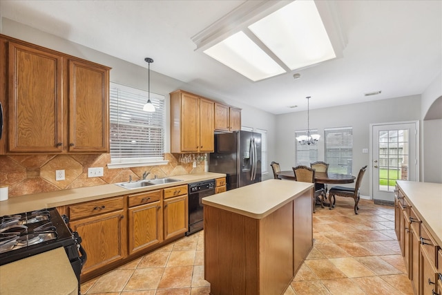 kitchen featuring a center island, light countertops, decorative backsplash, black appliances, and a sink