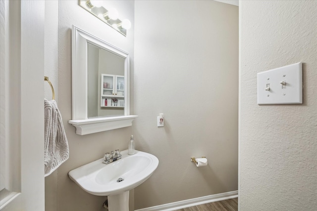 bathroom with a sink, baseboards, and wood finished floors