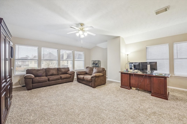 living area with baseboards, visible vents, ceiling fan, vaulted ceiling, and light colored carpet