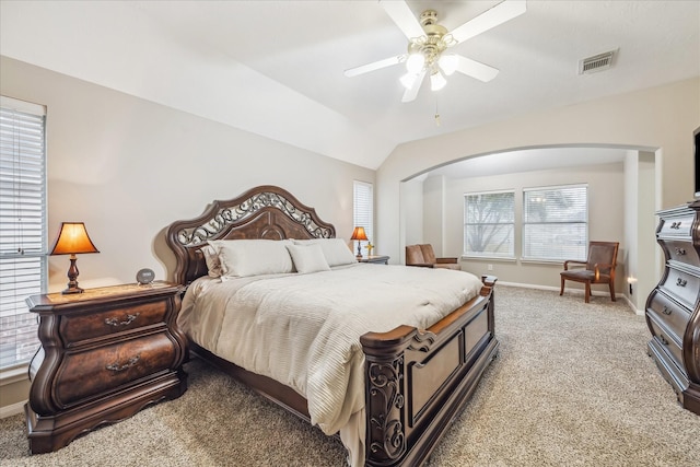 bedroom with visible vents, light carpet, arched walkways, baseboards, and vaulted ceiling