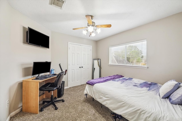 carpeted bedroom with visible vents, a textured ceiling, a closet, baseboards, and ceiling fan