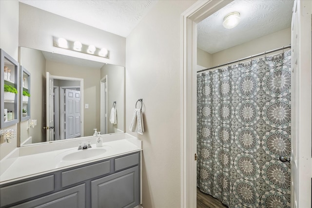 full bathroom with vanity, curtained shower, and a textured ceiling