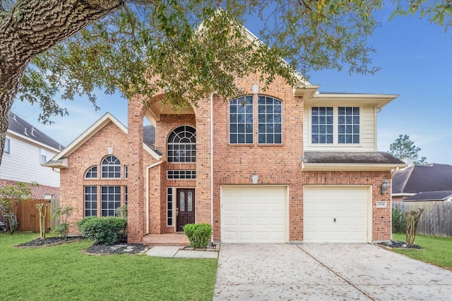 traditional-style house with brick siding, an attached garage, a front lawn, and fence