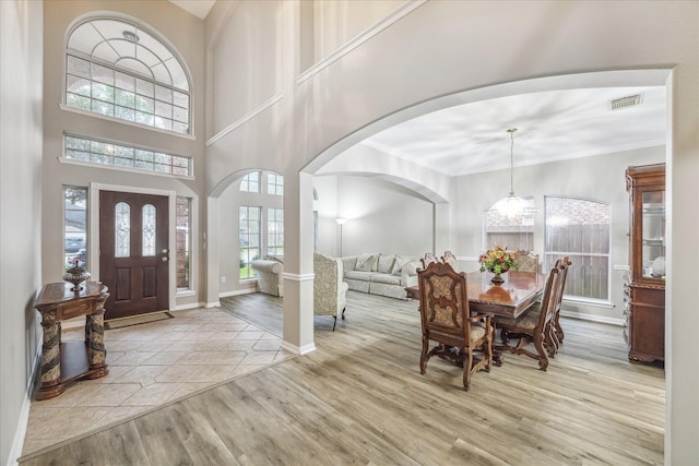 foyer entrance with visible vents, ornamental molding, wood finished floors, arched walkways, and baseboards