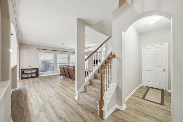 stairs featuring ceiling fan, baseboards, arched walkways, and wood finished floors