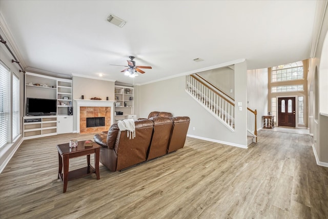 living area featuring visible vents, stairway, crown molding, and wood finished floors