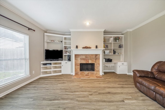 living area with baseboards, a fireplace, light wood-type flooring, and ornamental molding