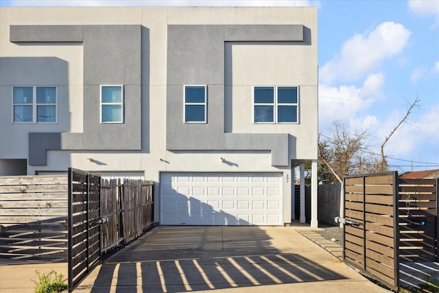 view of front facade with an attached garage, fence, driveway, and stucco siding