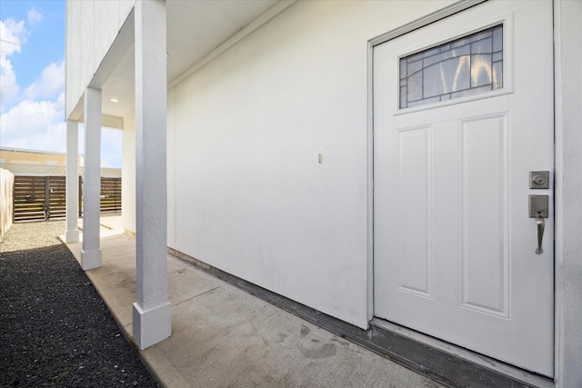 doorway to property featuring fence and stucco siding