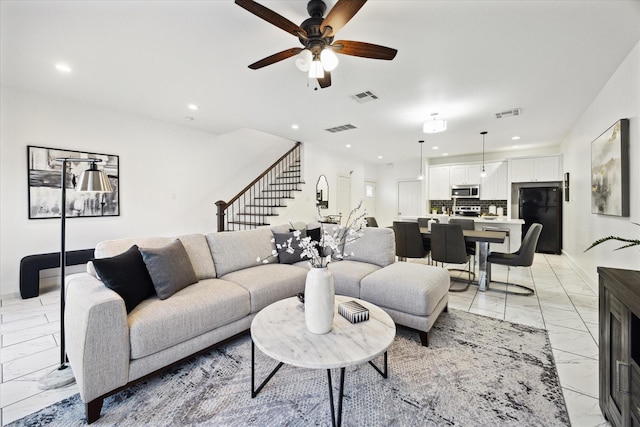 living area featuring visible vents, marble finish floor, ceiling fan, and stairway