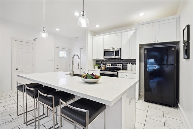 kitchen with a kitchen island with sink, a sink, decorative backsplash, appliances with stainless steel finishes, and marble finish floor