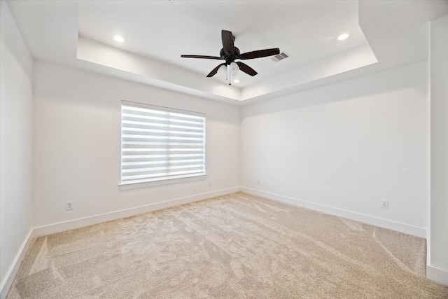 unfurnished room with visible vents, a raised ceiling, carpet, and baseboards