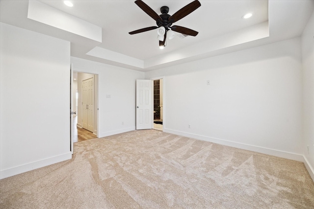 empty room with a ceiling fan, baseboards, recessed lighting, a raised ceiling, and light colored carpet