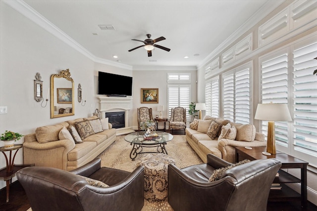 living area featuring a glass covered fireplace, visible vents, ceiling fan, and ornamental molding