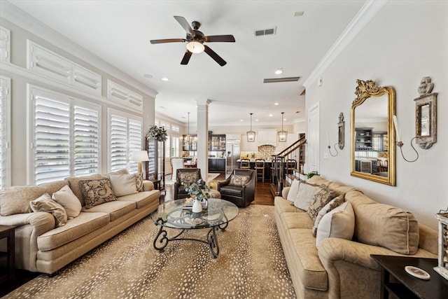 living room featuring visible vents, ornate columns, ceiling fan, stairs, and crown molding