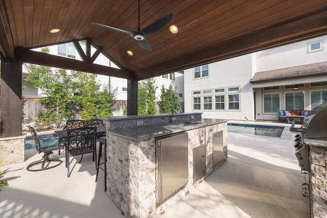 view of patio featuring area for grilling, fence, ceiling fan, and a sink