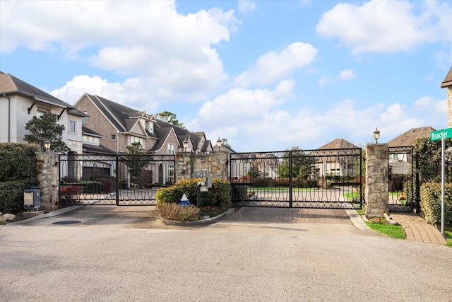 view of street with a gated entry, a residential view, street lighting, and a gate