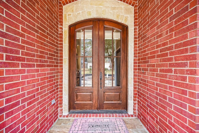 property entrance featuring brick siding and french doors