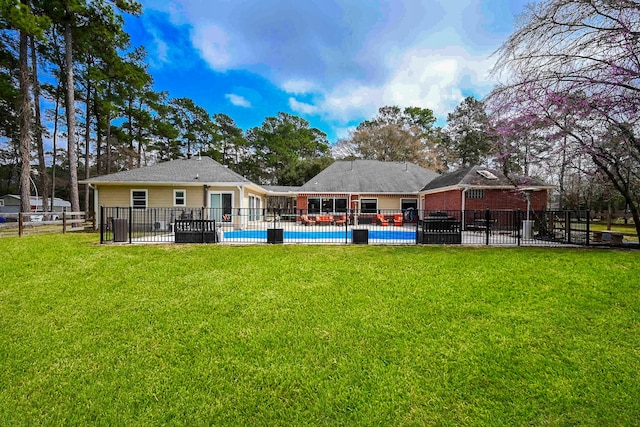 back of property with a patio area, a lawn, a fenced in pool, and fence