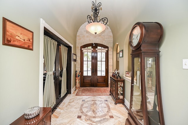 foyer with arched walkways, marble finish floor, french doors, and baseboards