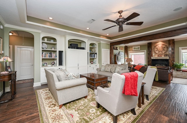 living area featuring visible vents, ceiling fan, a tiled fireplace, dark wood-style floors, and a raised ceiling