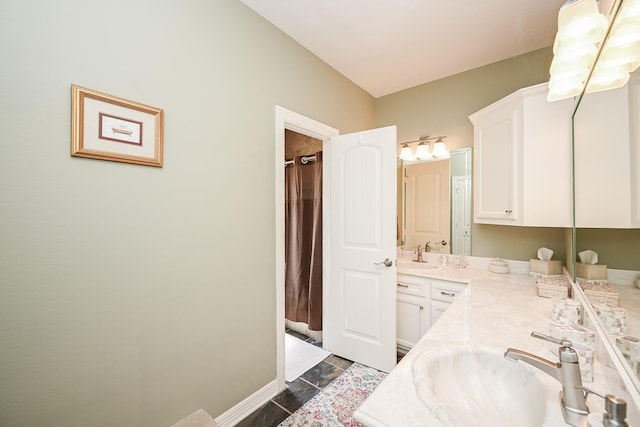 bathroom with double vanity, curtained shower, baseboards, and a sink