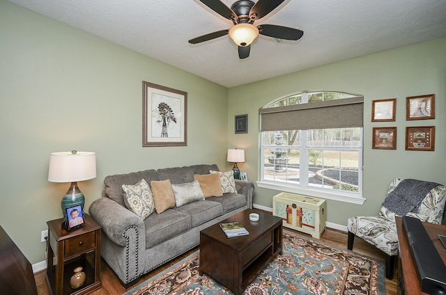 living area with baseboards, a textured ceiling, wood finished floors, and a ceiling fan