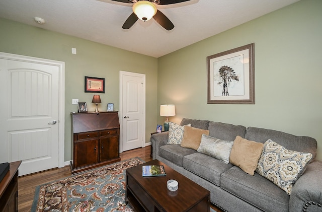 living room with baseboards, ceiling fan, and dark wood finished floors