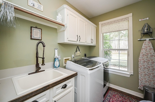 laundry area with wood finished floors, baseboards, cabinet space, a sink, and washer and dryer