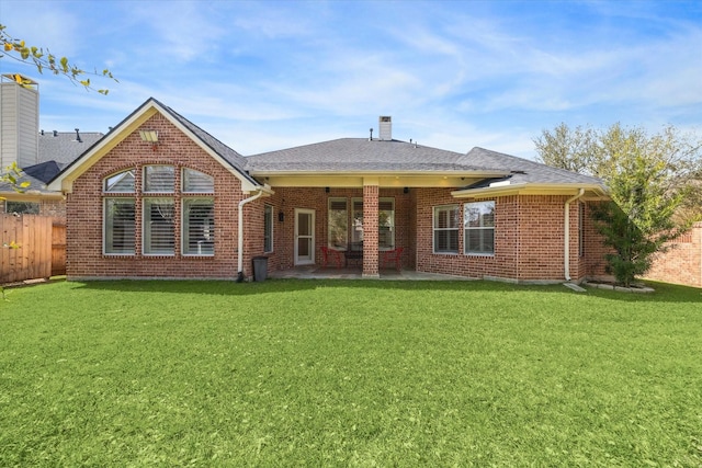 back of house with a patio area, a lawn, brick siding, and fence