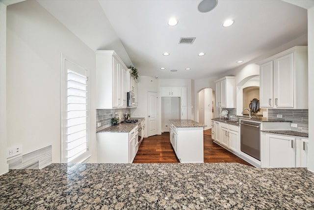 kitchen with visible vents, dark wood-style flooring, arched walkways, appliances with stainless steel finishes, and backsplash