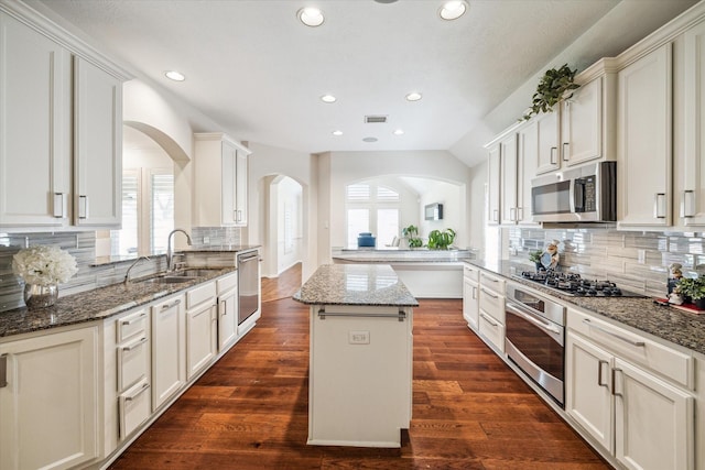 kitchen with visible vents, arched walkways, dark wood-style flooring, a sink, and stainless steel appliances