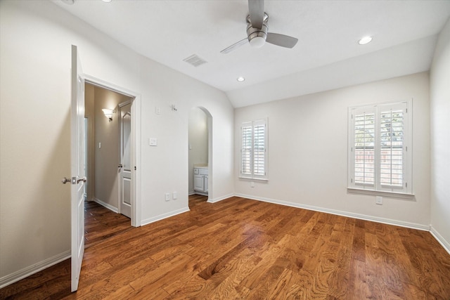 unfurnished bedroom with wood finished floors, arched walkways, visible vents, and lofted ceiling