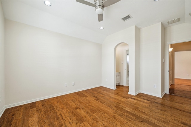 unfurnished room with a ceiling fan, wood finished floors, arched walkways, and visible vents