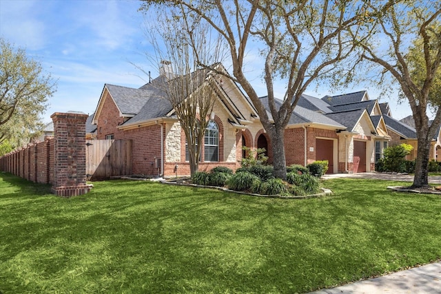 view of home's exterior with brick siding, an attached garage, a yard, and fence