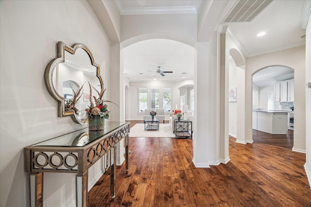 hallway with arched walkways, visible vents, dark wood finished floors, and crown molding