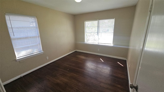 unfurnished room with dark wood-type flooring and baseboards