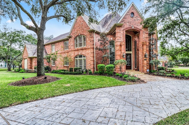 tudor home featuring brick siding and a front yard