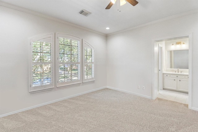 spare room featuring visible vents, light carpet, a sink, crown molding, and ceiling fan