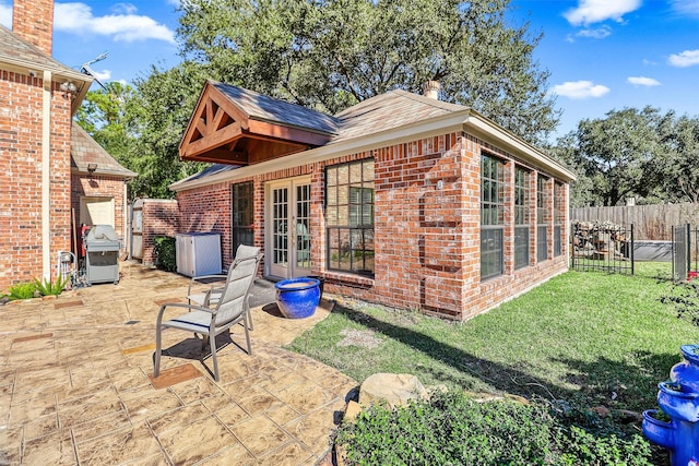 back of house with fence, a yard, french doors, a patio area, and brick siding