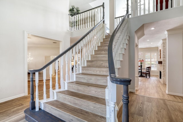 stairway with crown molding, wood finished floors, and baseboards