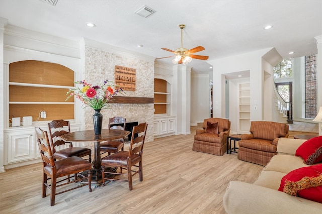 dining space featuring light wood finished floors, visible vents, built in features, stairs, and a ceiling fan