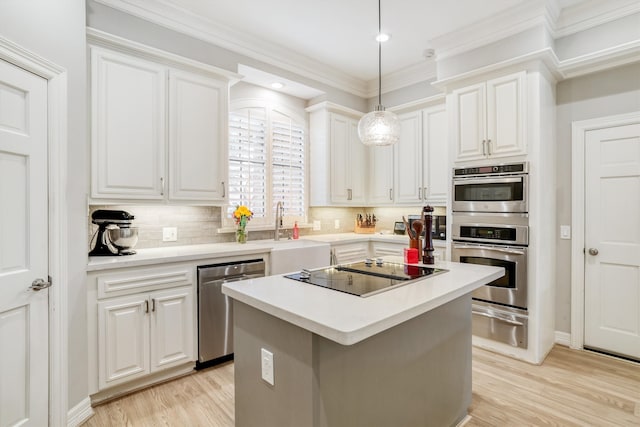 kitchen featuring a warming drawer, ornamental molding, a sink, stainless steel appliances, and light wood finished floors