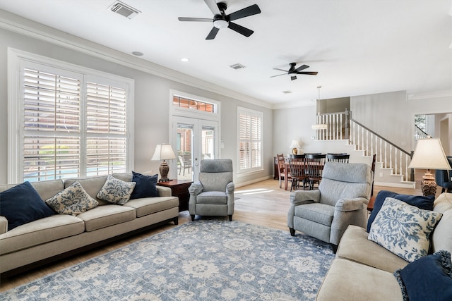 living area with visible vents, light wood-style flooring, a ceiling fan, stairway, and crown molding