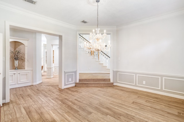 unfurnished dining area with a decorative wall, visible vents, light wood finished floors, and a chandelier