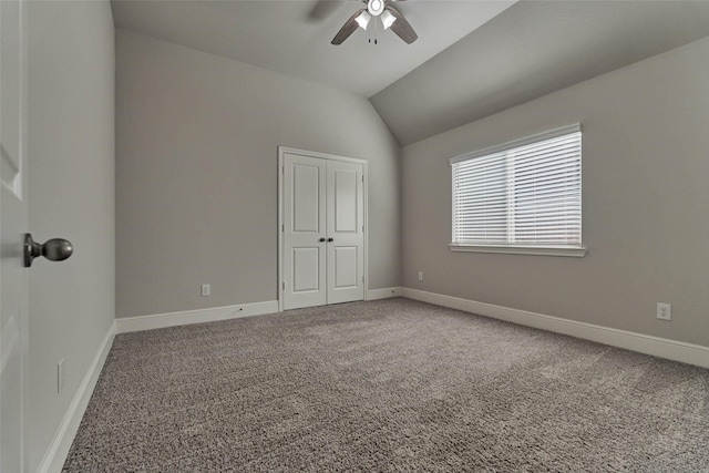 interior space with a ceiling fan, lofted ceiling, carpet, and baseboards